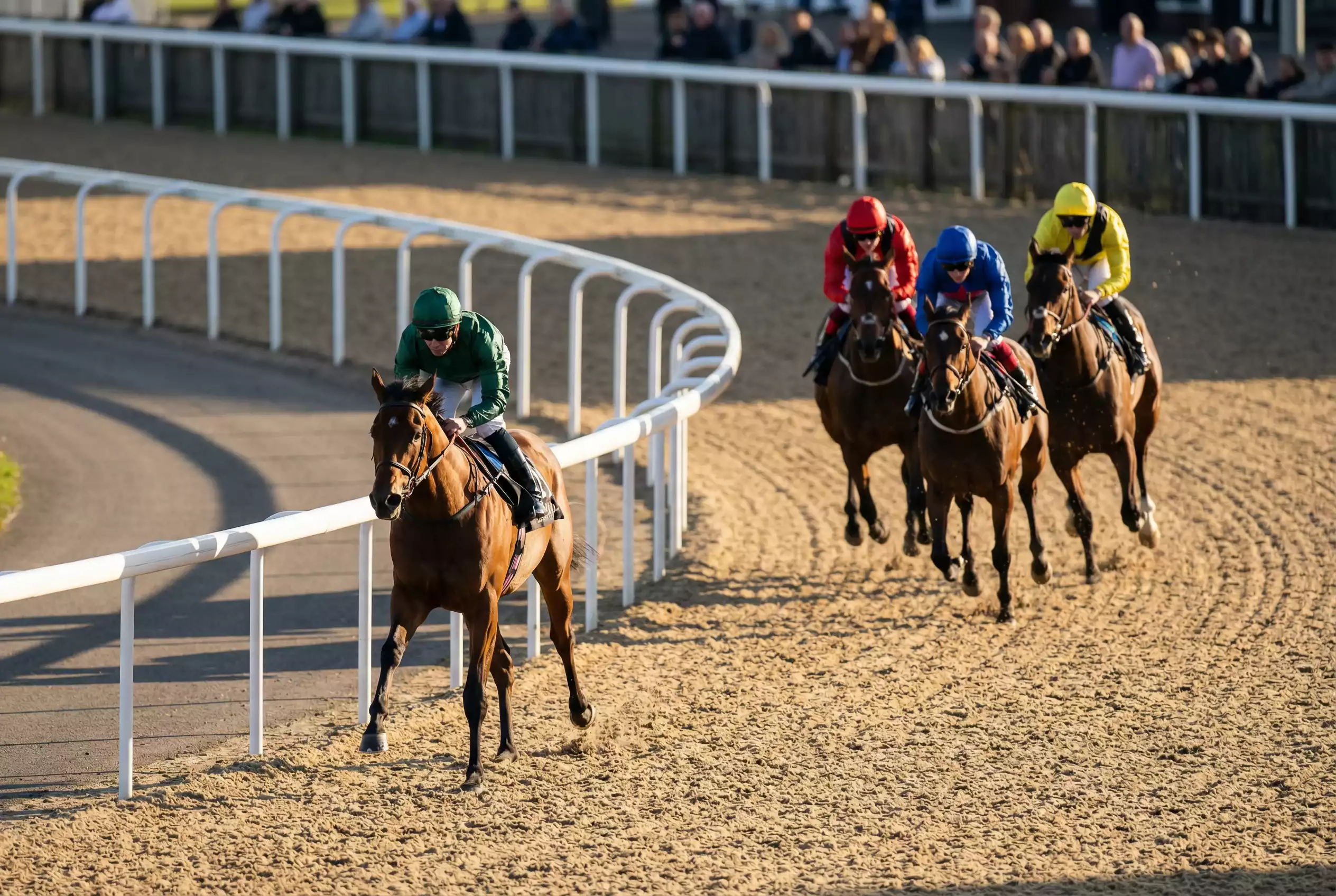 A front-running horse leading the field around the bend at Southwell on the Tapeta track