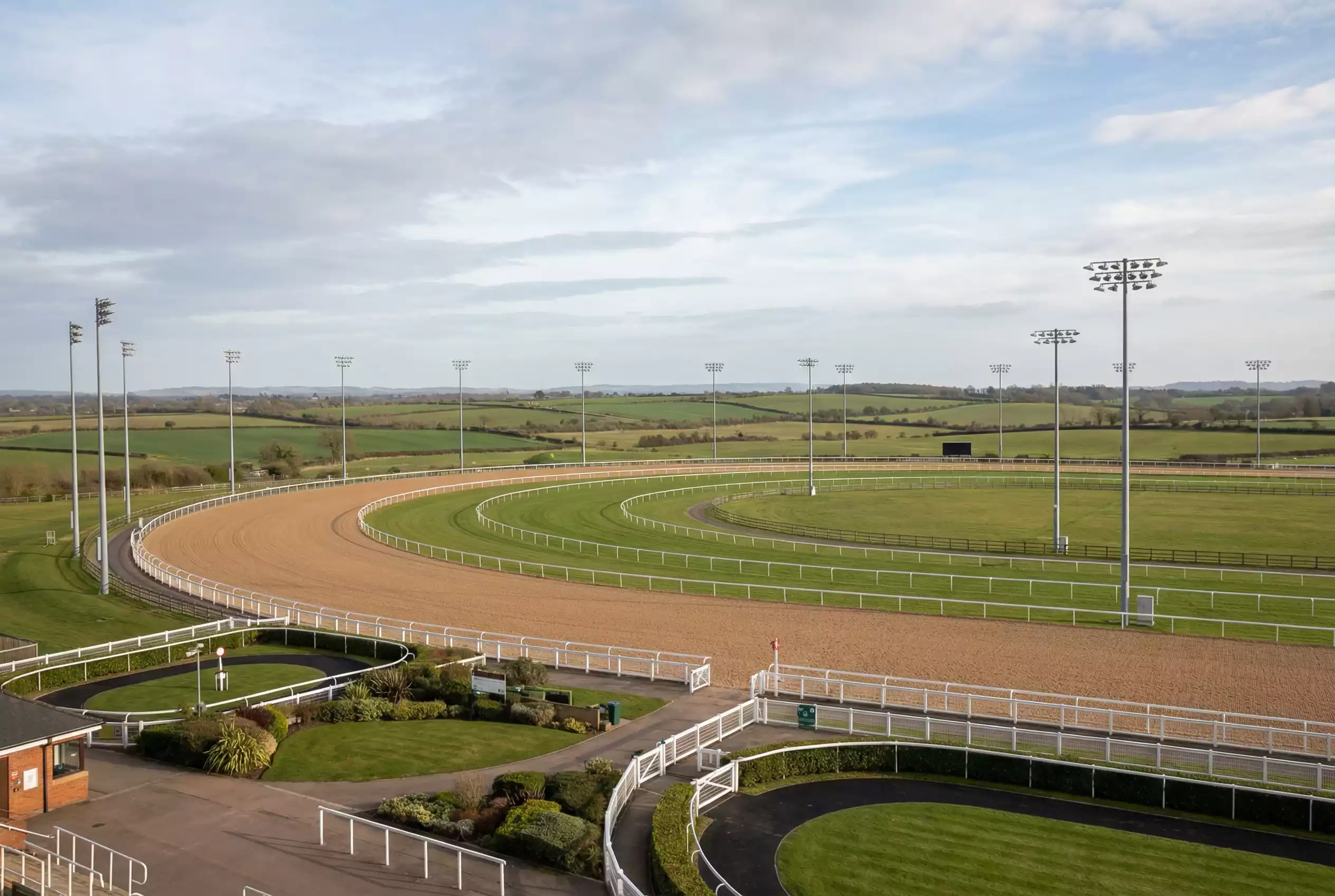 Southwell Racecourse all-weather Tapeta track viewed from the grandstand with floodlights and the Nottinghamshire countryside beyond