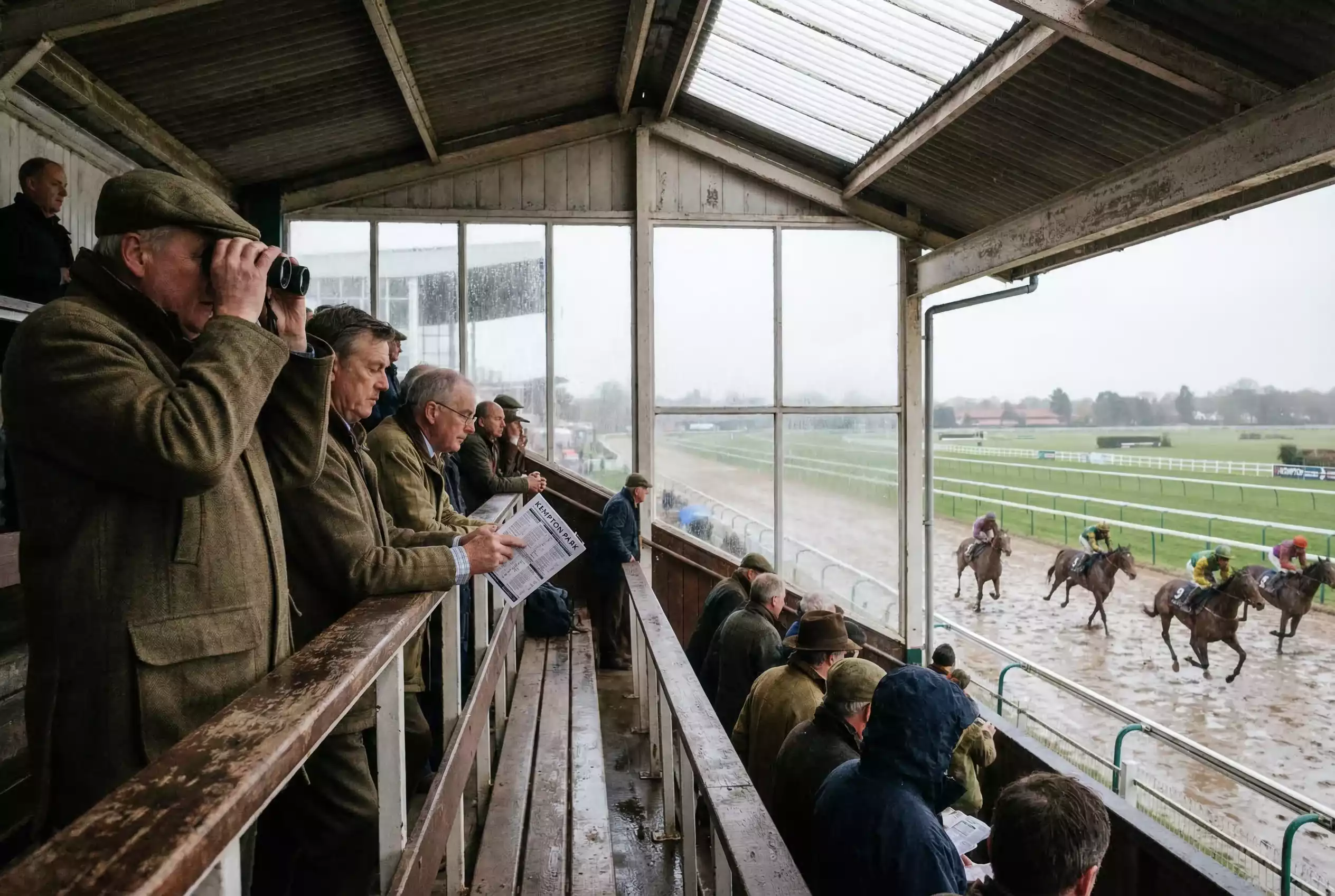 Racegoers watching live racing from the Southwell grandstand with binoculars